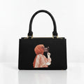 Black structured top-handle handbag with illustrated front panel and gold-tone hardware